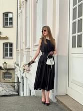 a lady wears a black knitted maxi vest dress with belt